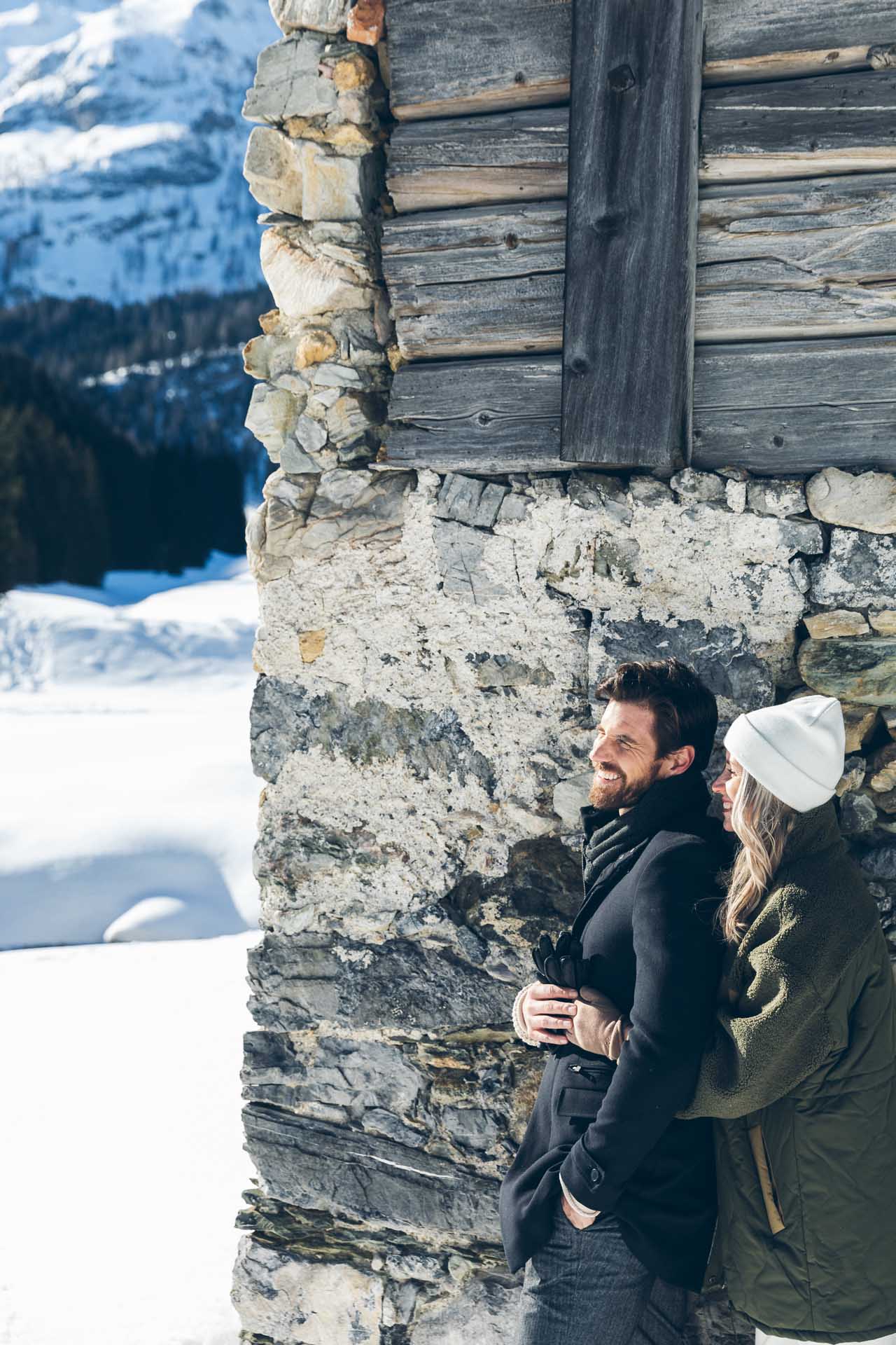 Pärchen an Hausmauer mit Winterlandschaft im Hintergrund